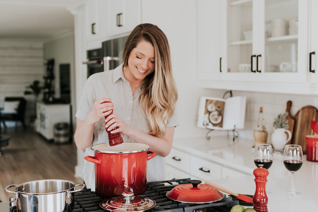 smiling-woman-standing-and-putting-pepper-on-stock-pot-rjmgztg4-mw